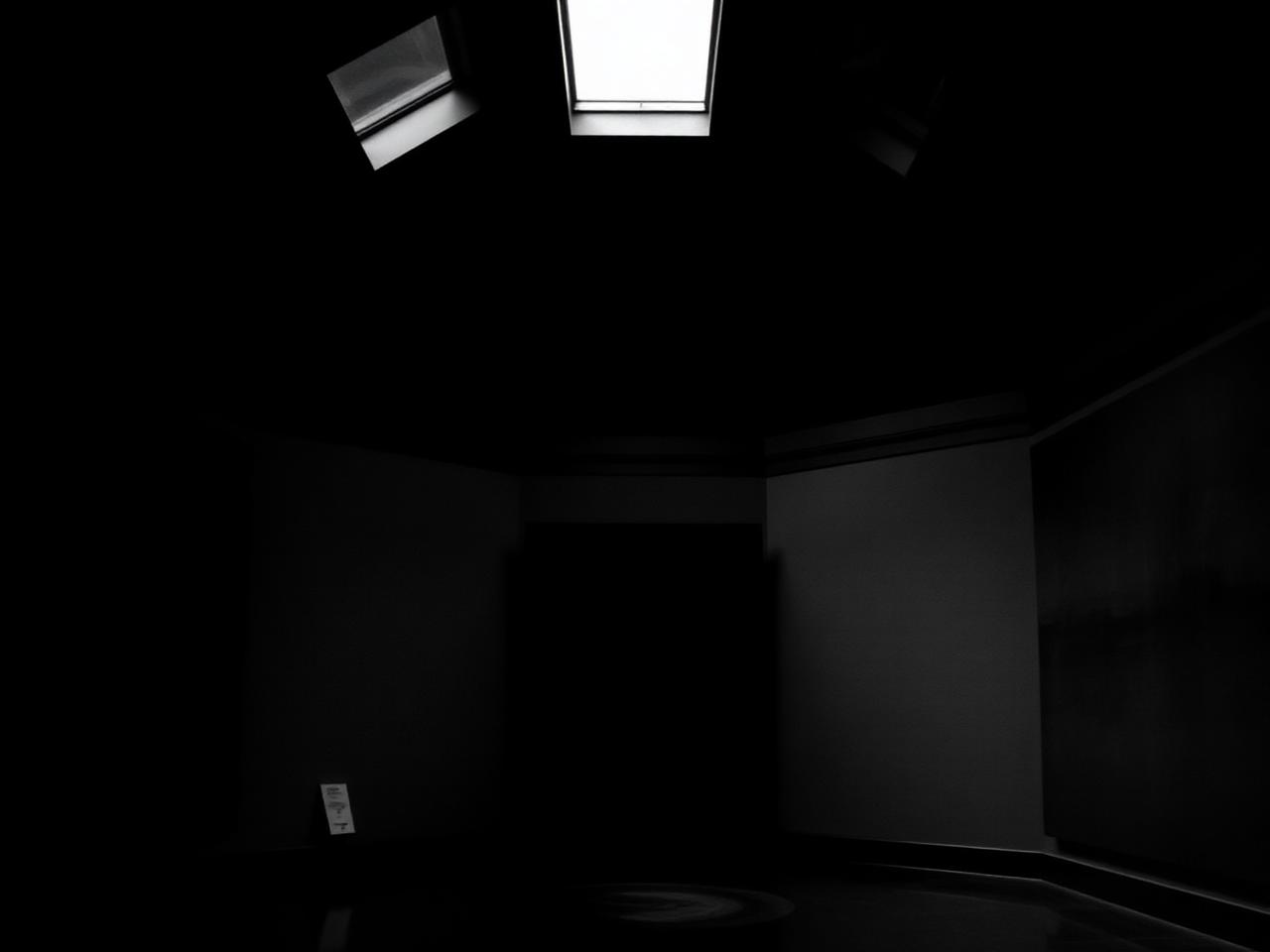 Dark contemplative interior of the Rothko Chapel with a single skylight